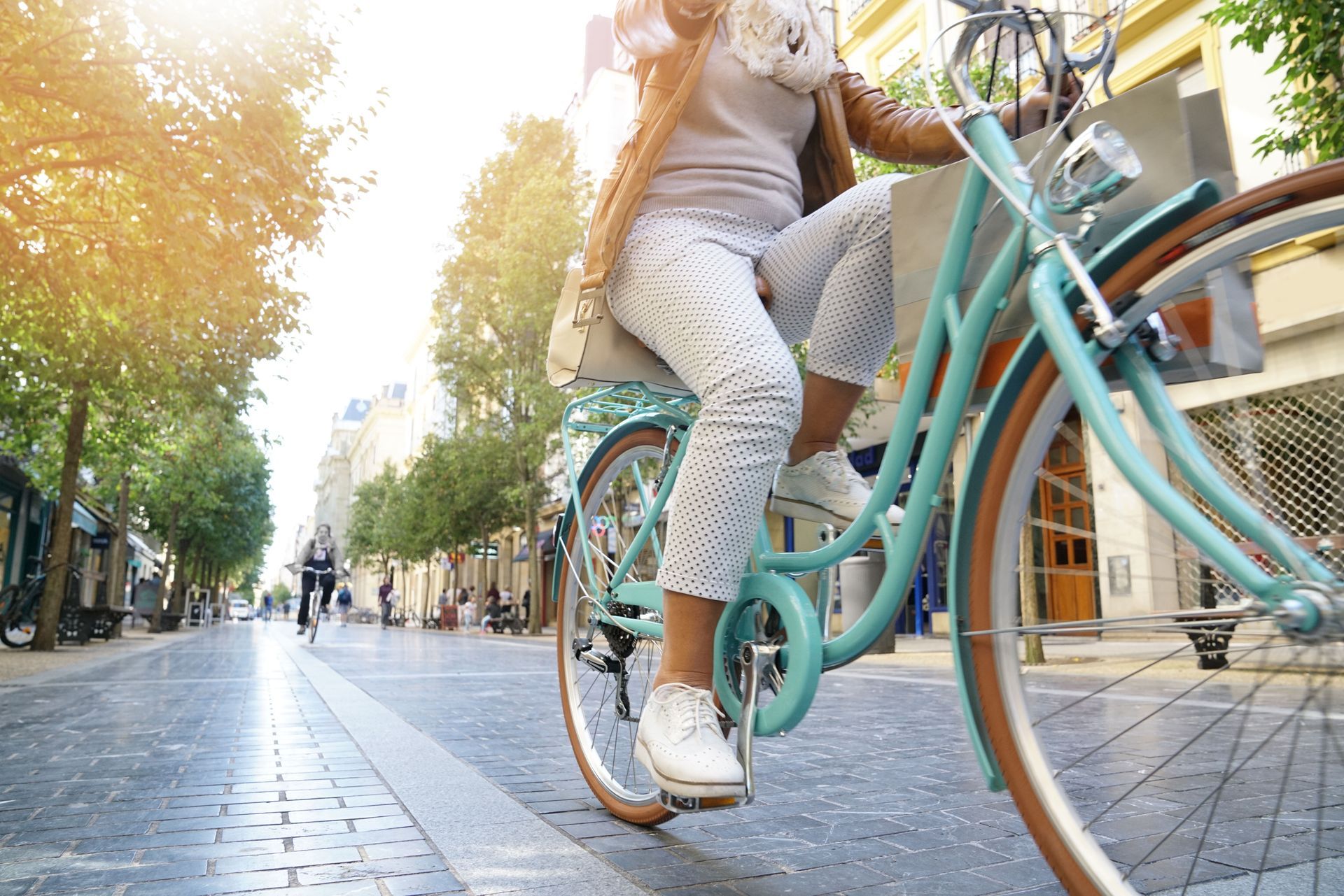 Femme sur son vélo bleu dans une rue pavée