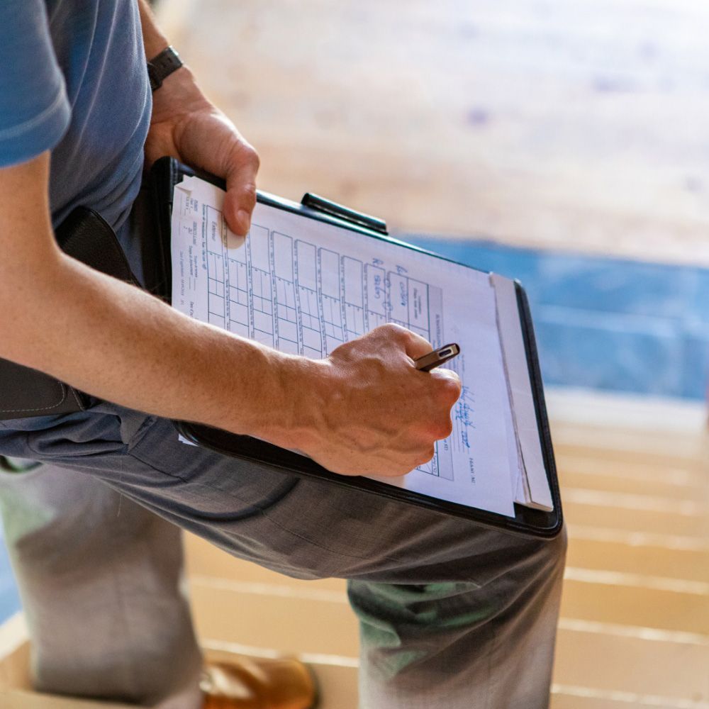Person holding a clipboard and writing on a form indoors.