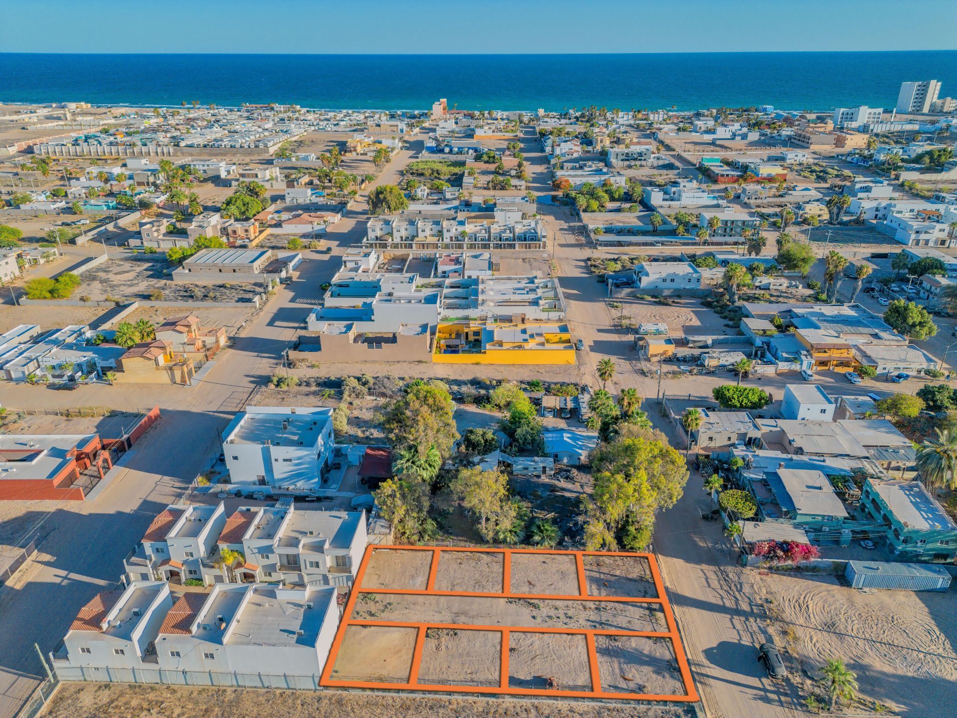 Aerial view of a coastal town with grid streets, low buildings, and the ocean in the distance