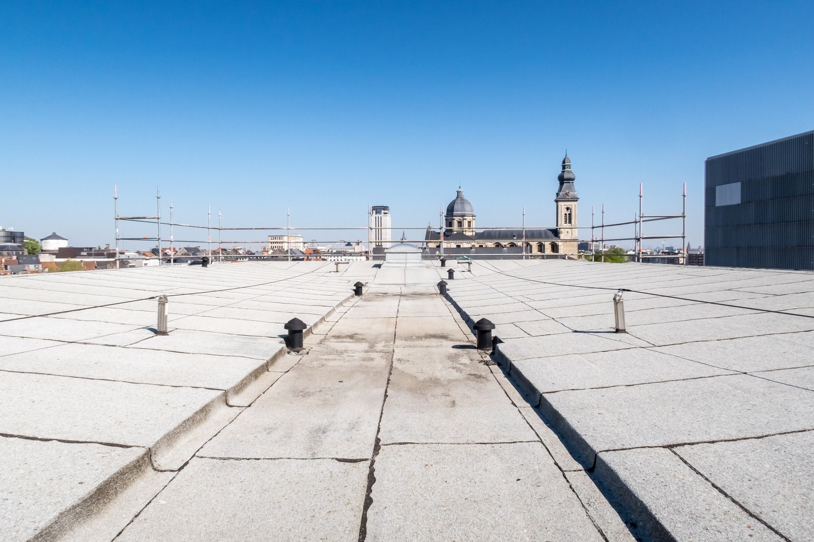 Rooftop terrace with white stone tiles and distant city skyline under a clear blue sky