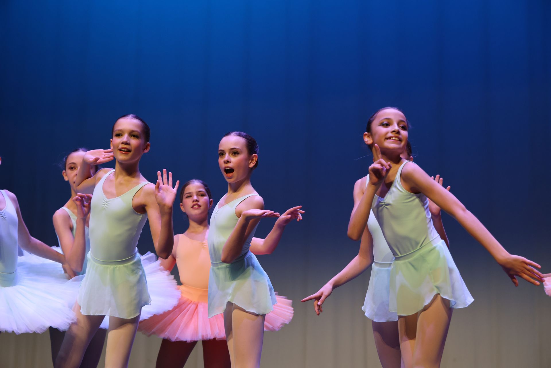 Une jeune ballerine en robe blanche saute dans les airs.