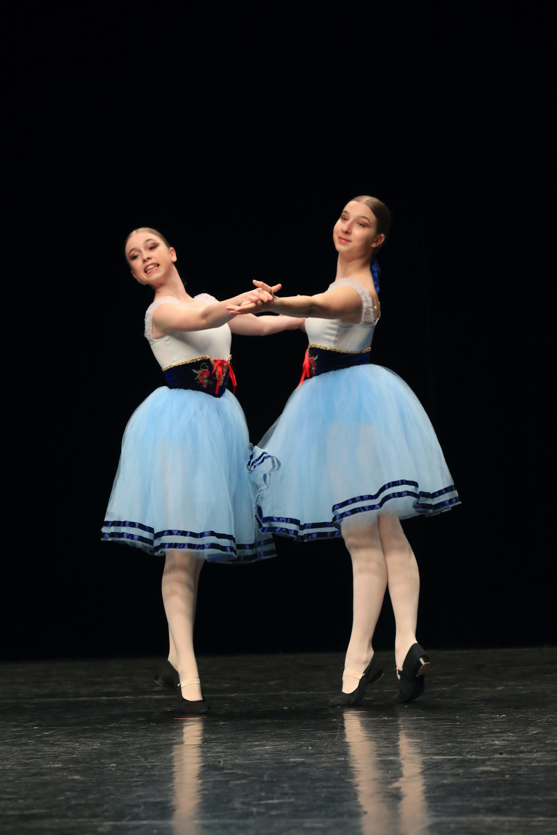 Un groupe de danseurs de ballet se tiennent côte à côte sur une piste de danse.