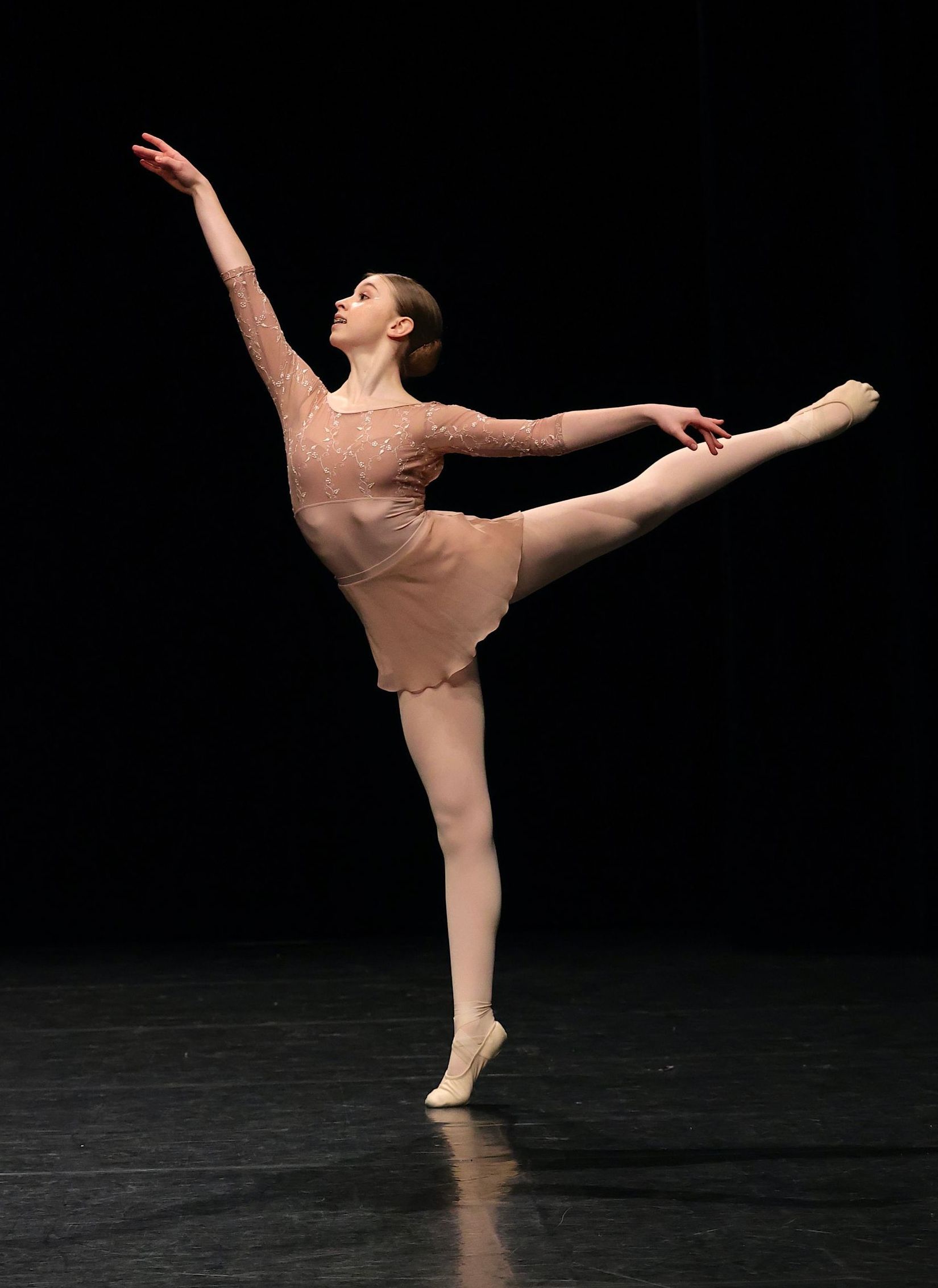 Une jeune ballerine en robe blanche saute dans les airs.