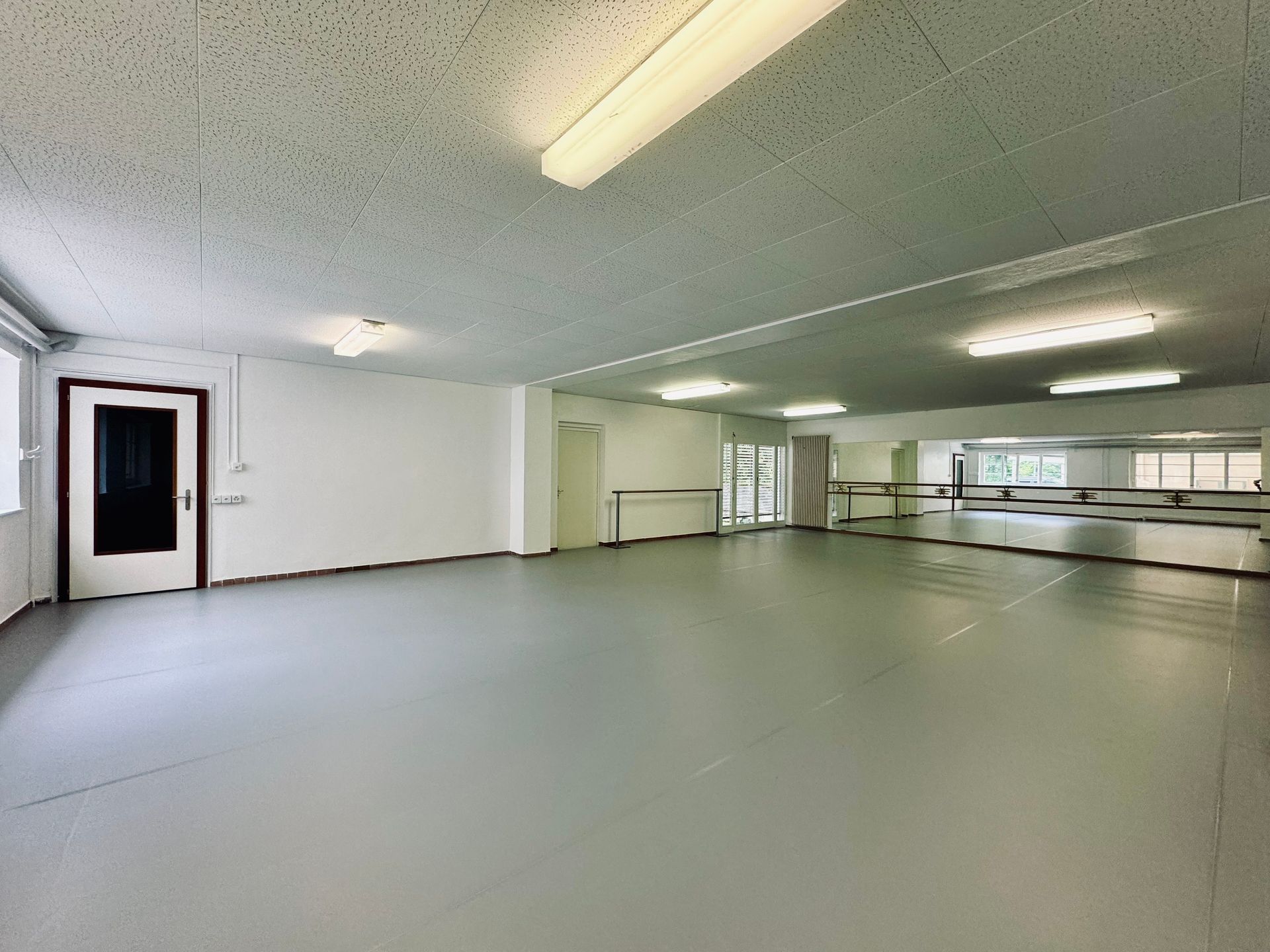 Une ballerine danse devant une fenêtre dans une pièce.