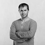 Un homme est debout avec les bras croisés sur une photo en noir et blanc.