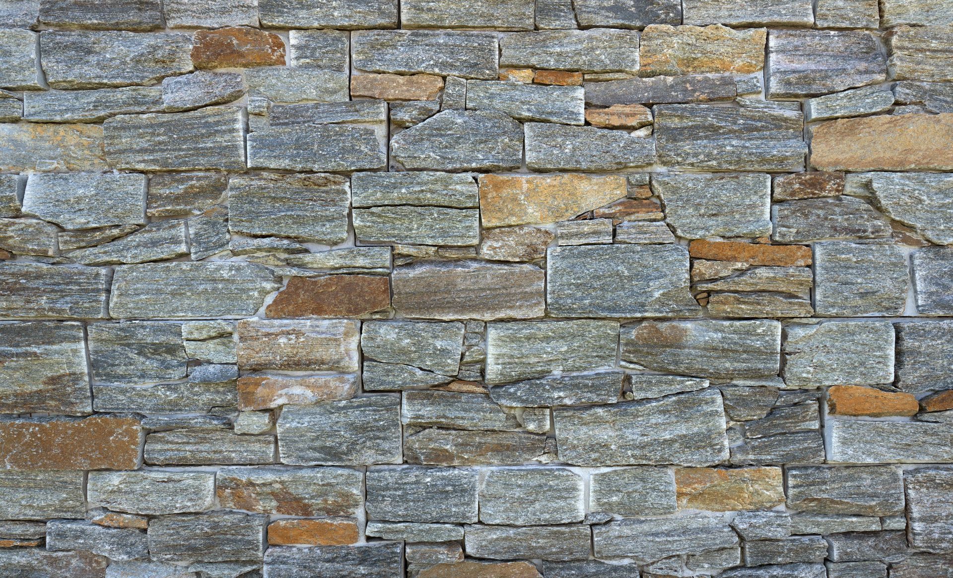 Mur en pierre composé de blocs rectangulaires gris et bruns.