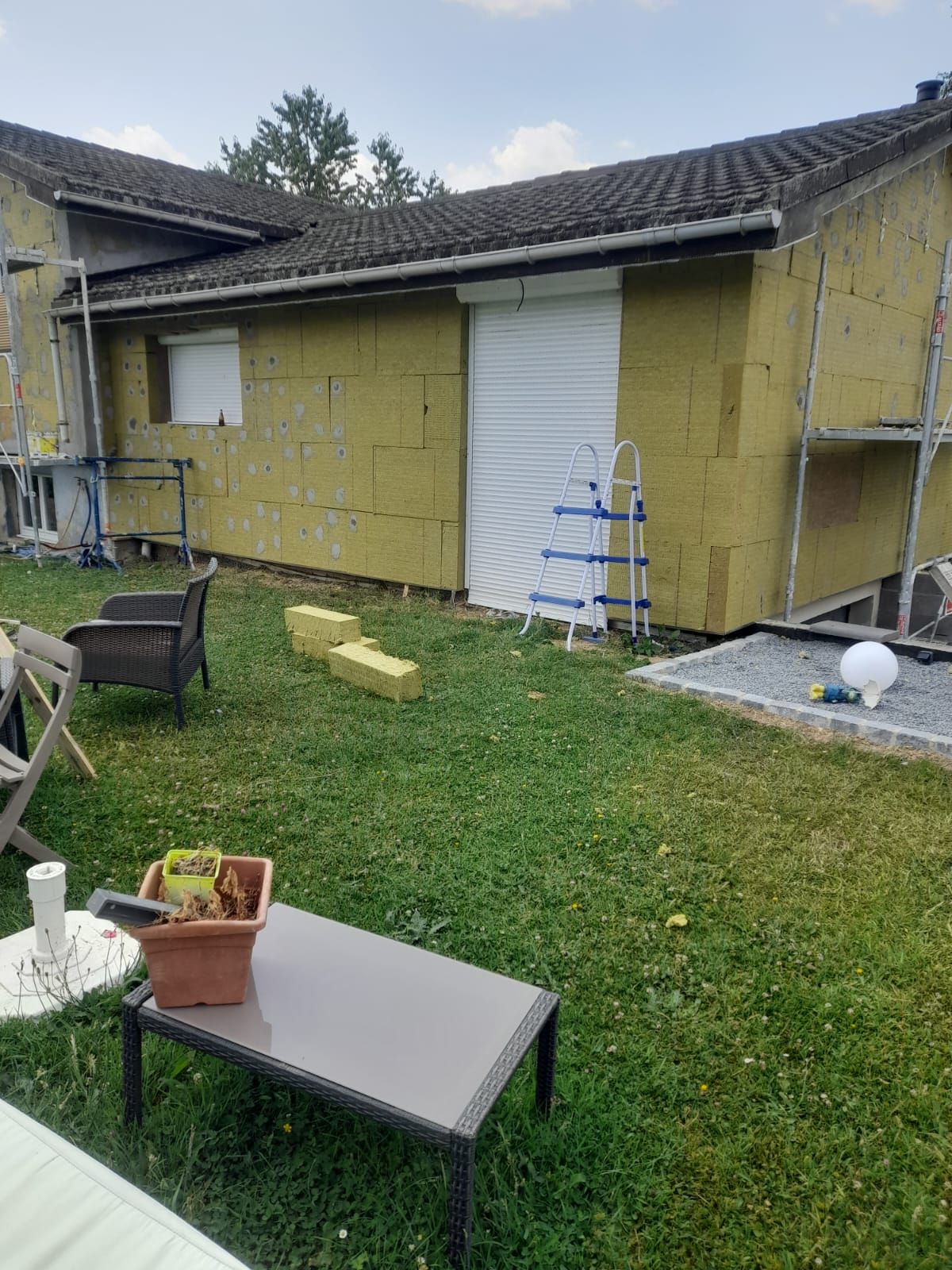 Extérieur de la maison avec isolation jaune en cours d'installation sur les murs.