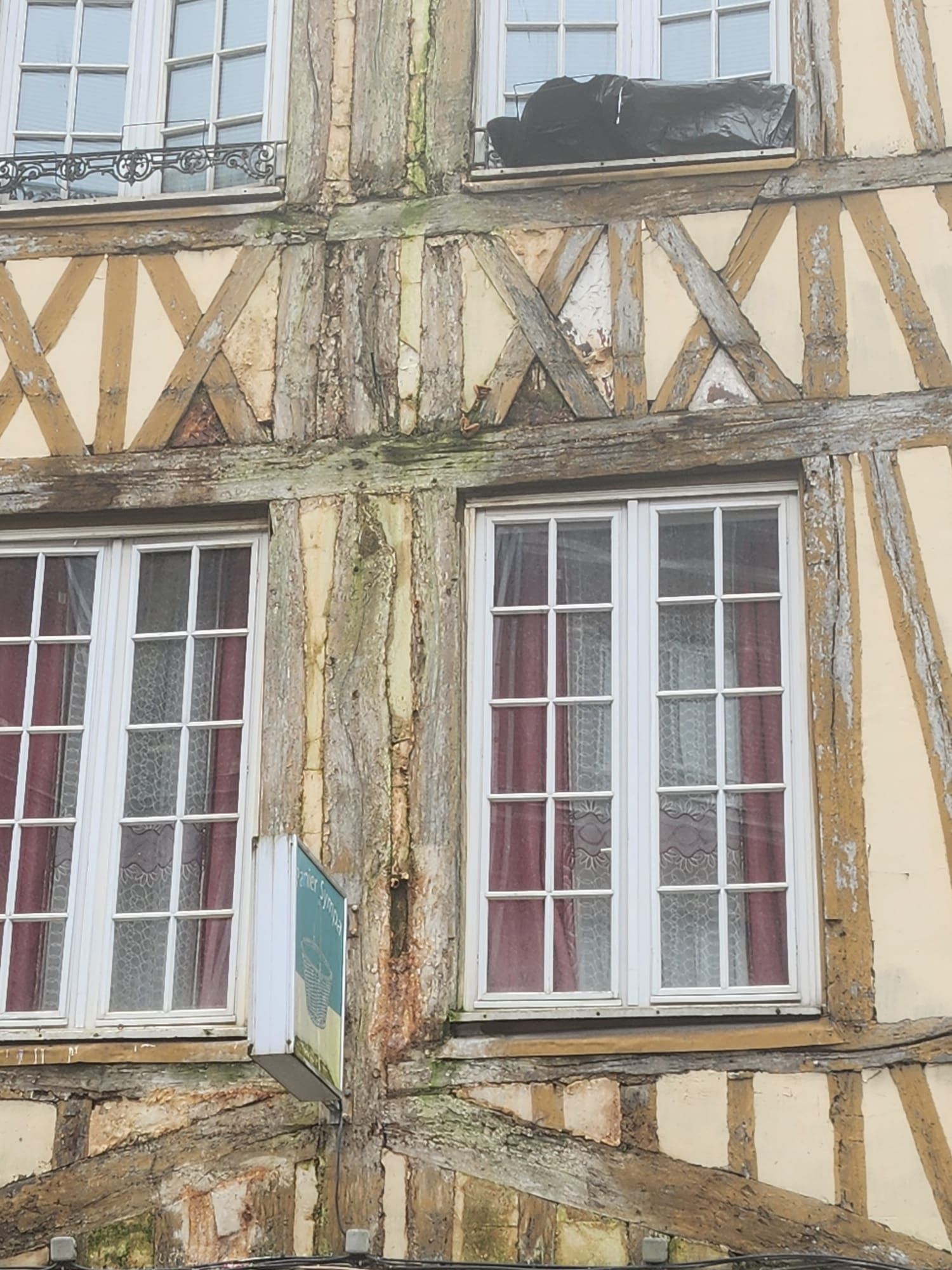 Façade d'un bâtiment à ossature en bois avec fenêtres à cadre blanc, murs beiges et poutres brunes.