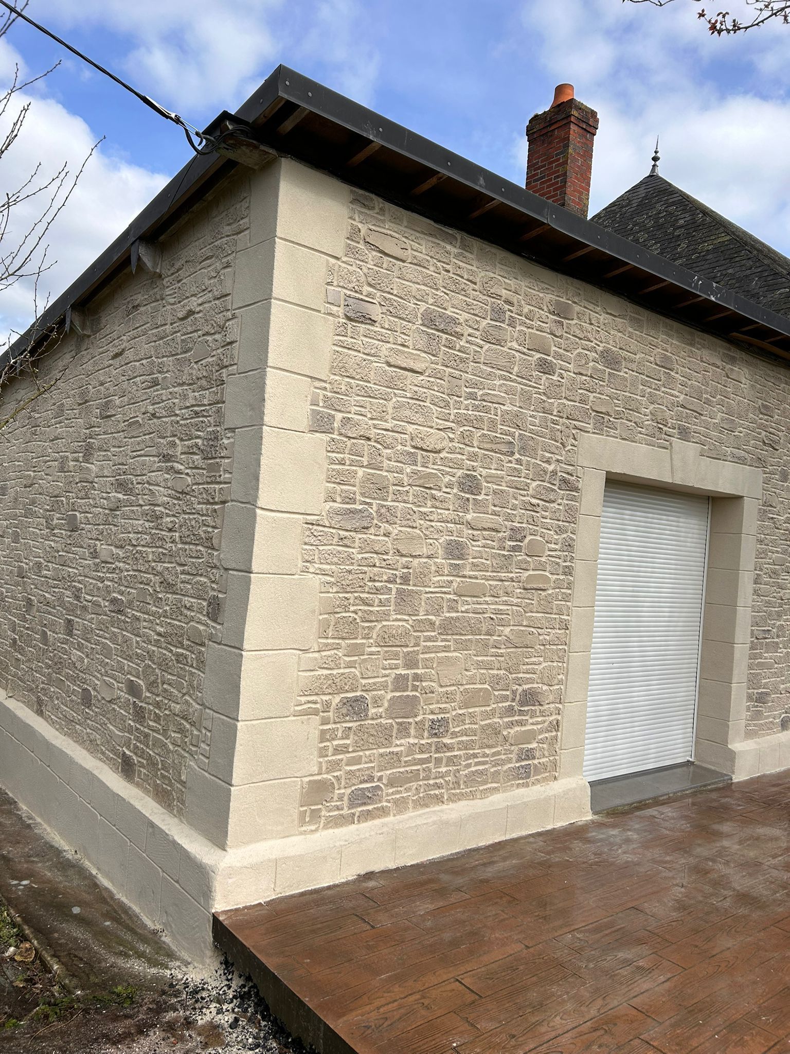 Bâtiment en pierre avec une porte blanche ornée de volutes et une rampe en métal patiné.
