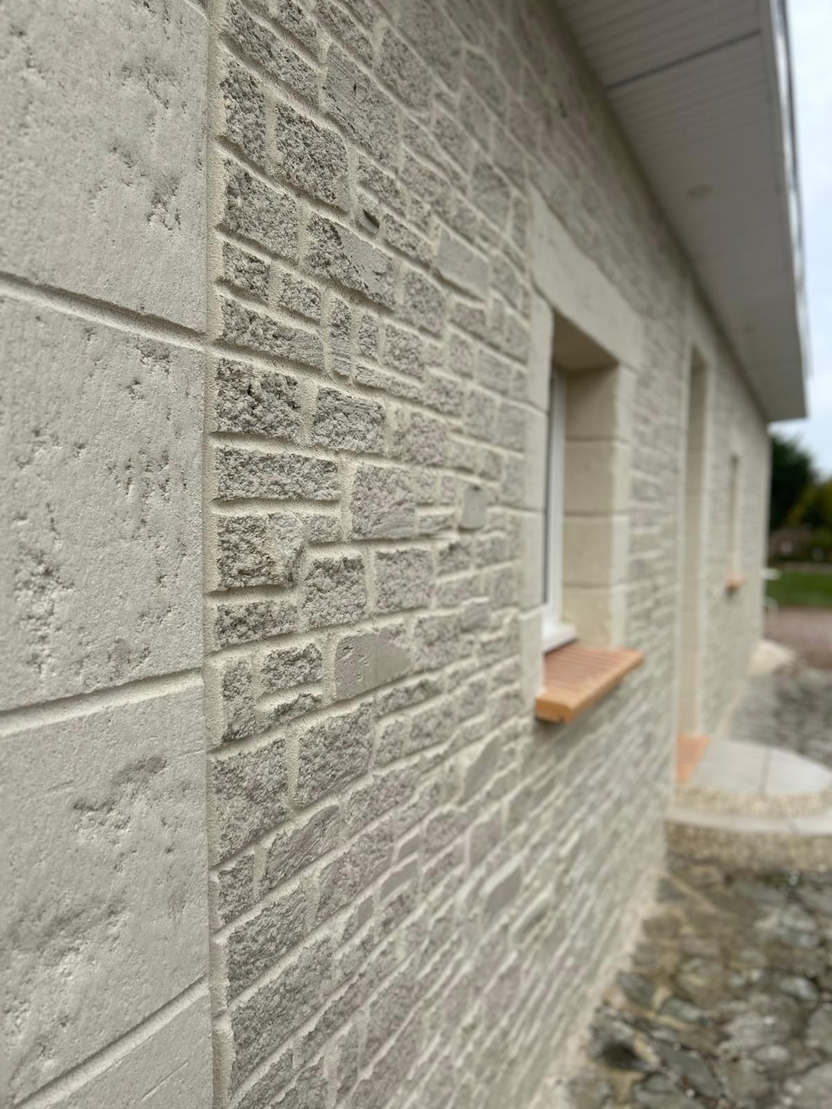Maison beige en construction, avec un toit de tuiles rouges et un ciel gris foncé.