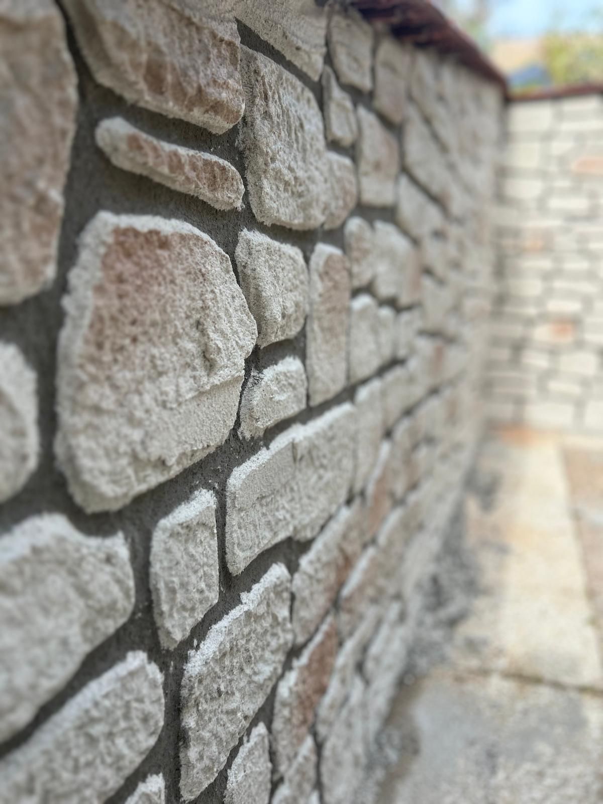 Mur en pierre de tailles et de formes variées. Joints de mortier foncés.