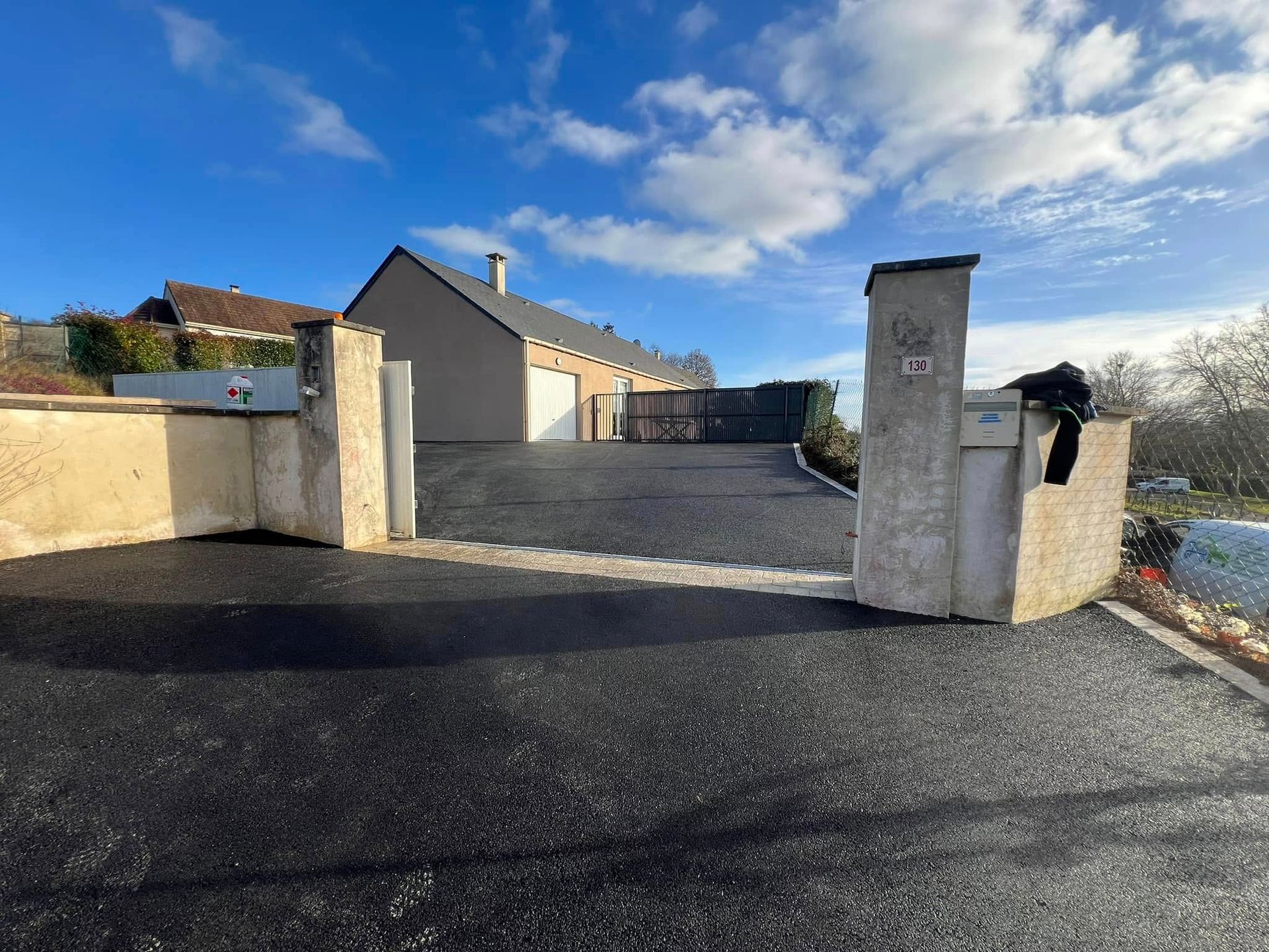 Pose d'enrobé à chaud noir avec seuil de portail en pavés ton pierre