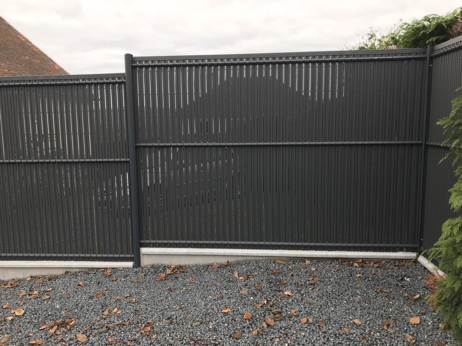 Installation d'une clôture en panneaux rigides gris avec occultants en bois et soubassements en béton 