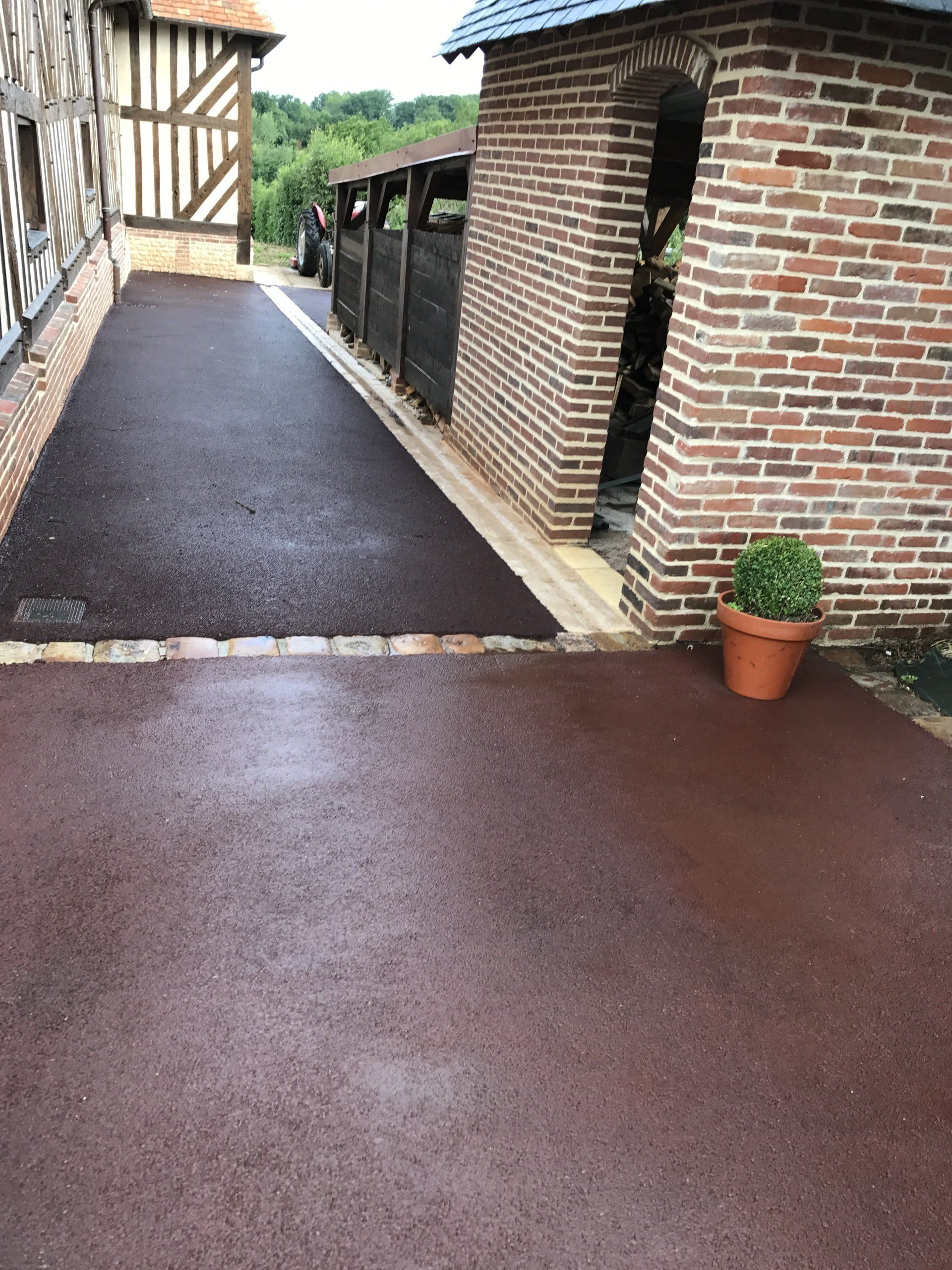 Pose d'un enrobé à chaud noir avec forme et bordures en pavés ton pierre 