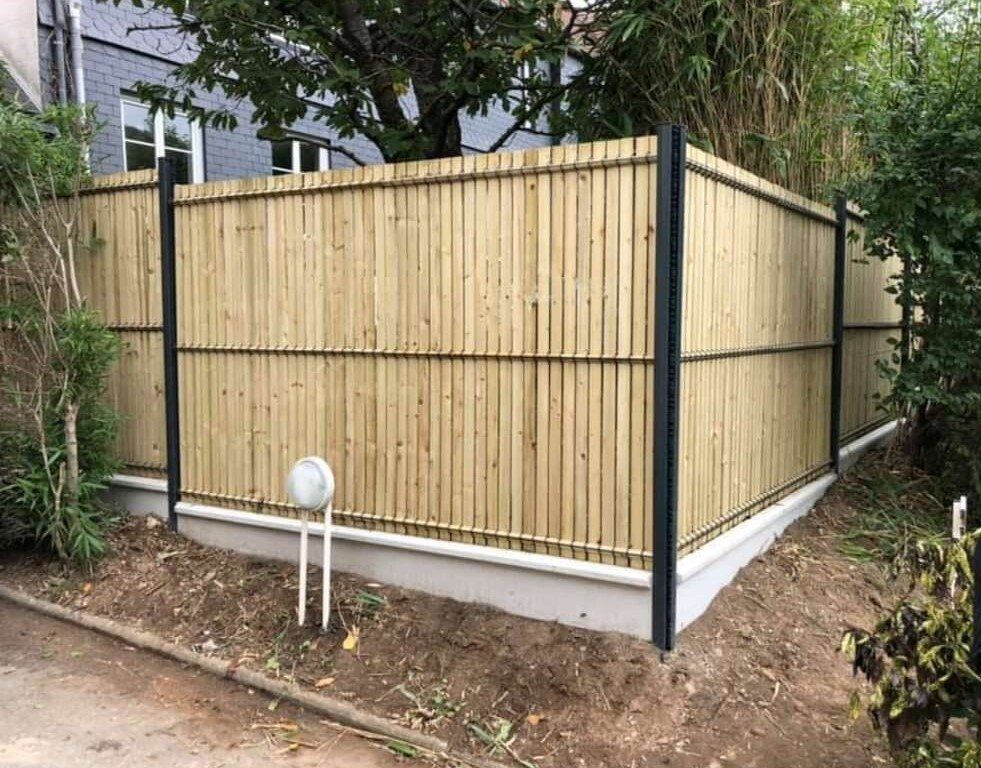 Installation d'une clôture en panneaux rigides gris avec occultants en bois et soubassements en béton 