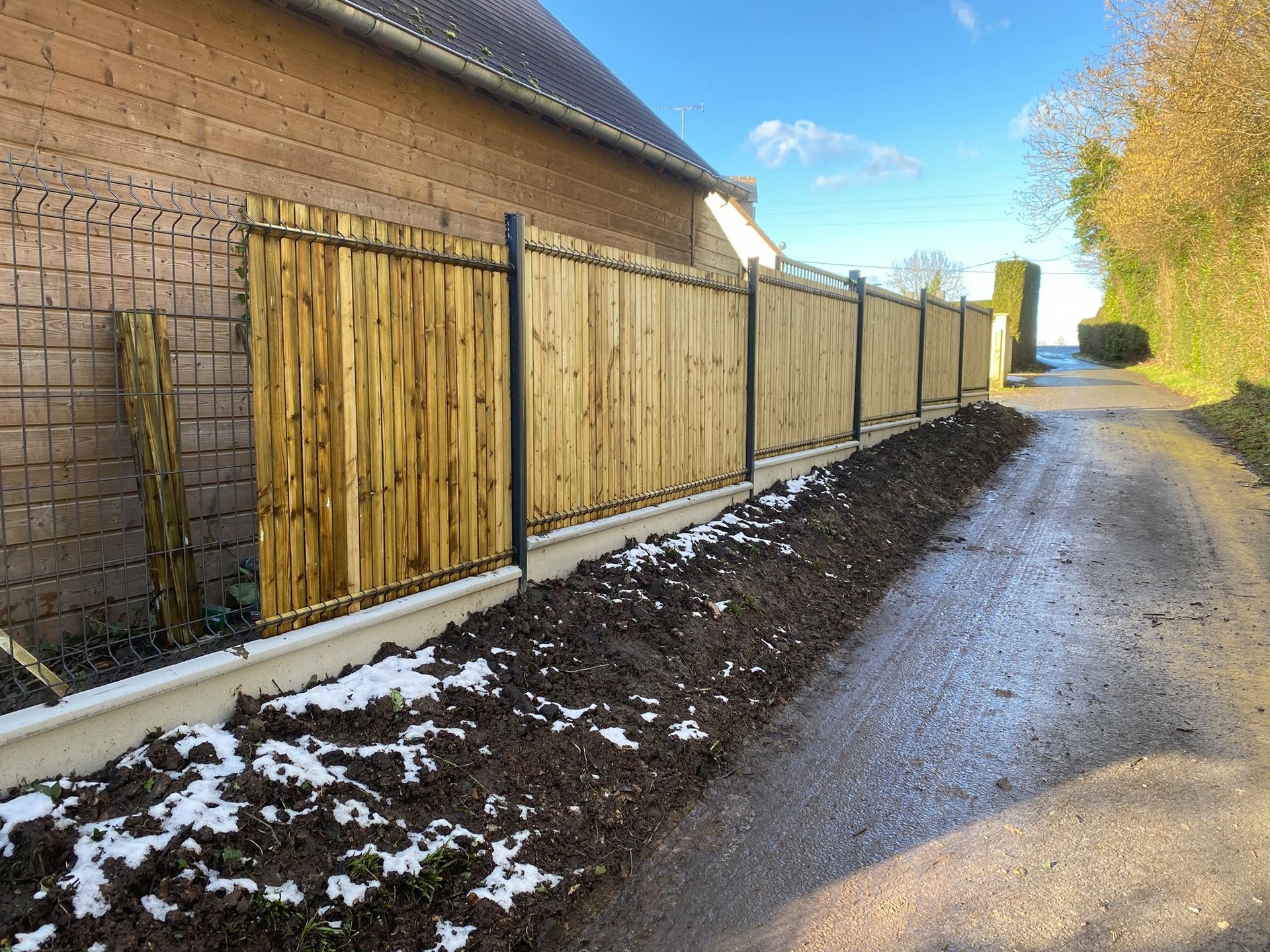 Installation d'une clôture en panneaux rigides gris avec occultants en pvc et soubassements en béton 