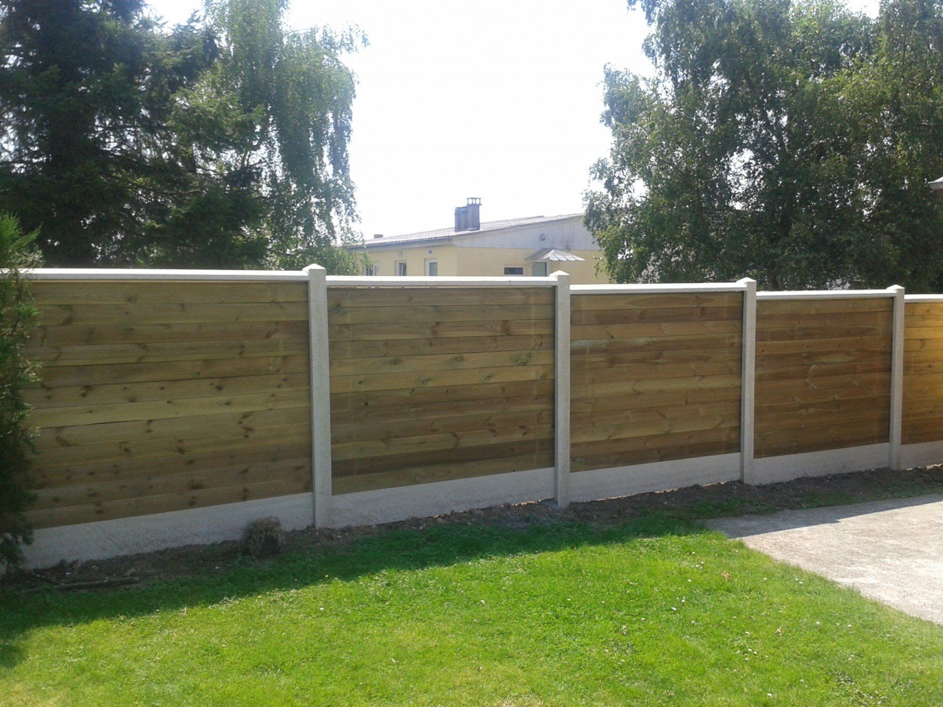 Installation d'une clôture en panneaux rigides gris avec occultants bois et soubassements en béton 