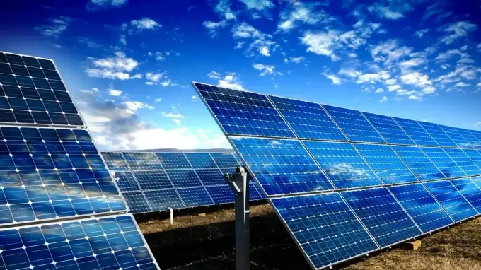 Paneles solares contra un cielo azul con nubes.