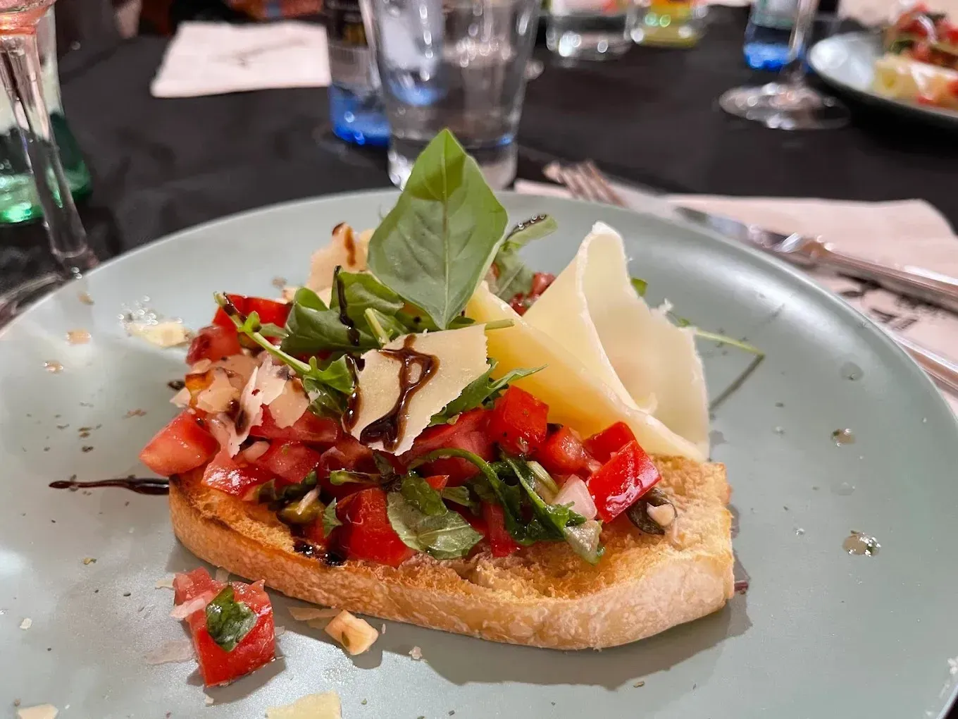 Bruschetta con albahaca y queso rallado en un plato en la mesa de un restaurante.