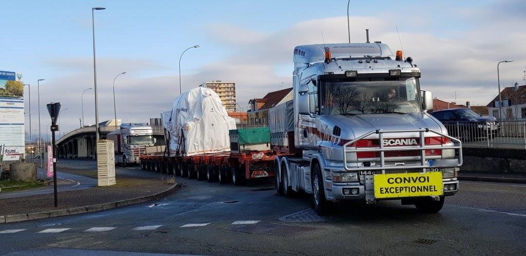 Long convoi exceptionnel franchissant un virage routier