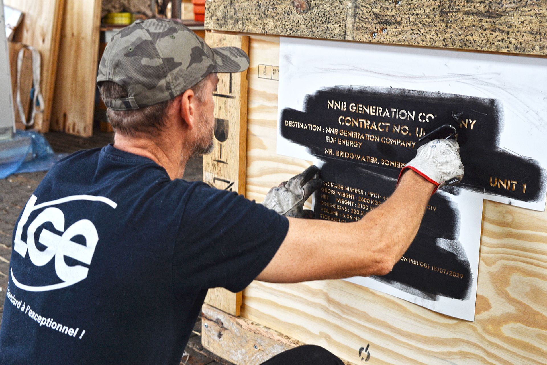 Un peintre opposant du marquage sur un colis en bois