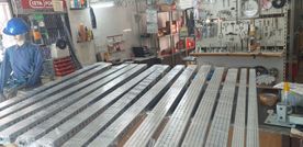 Un hombre con un casco azul está parado en una habitación llena de muchas piezas de metal.