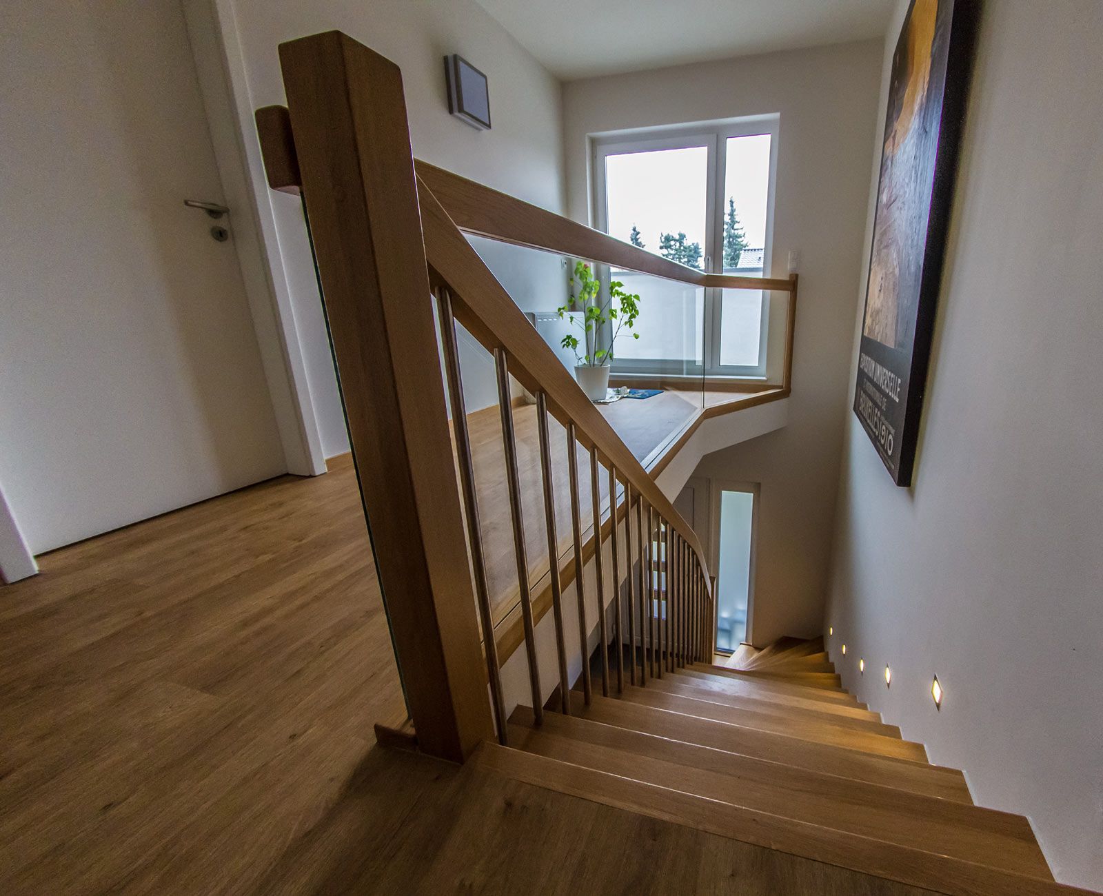 Eine Holztreppe mit Glasgeländer und Fenster