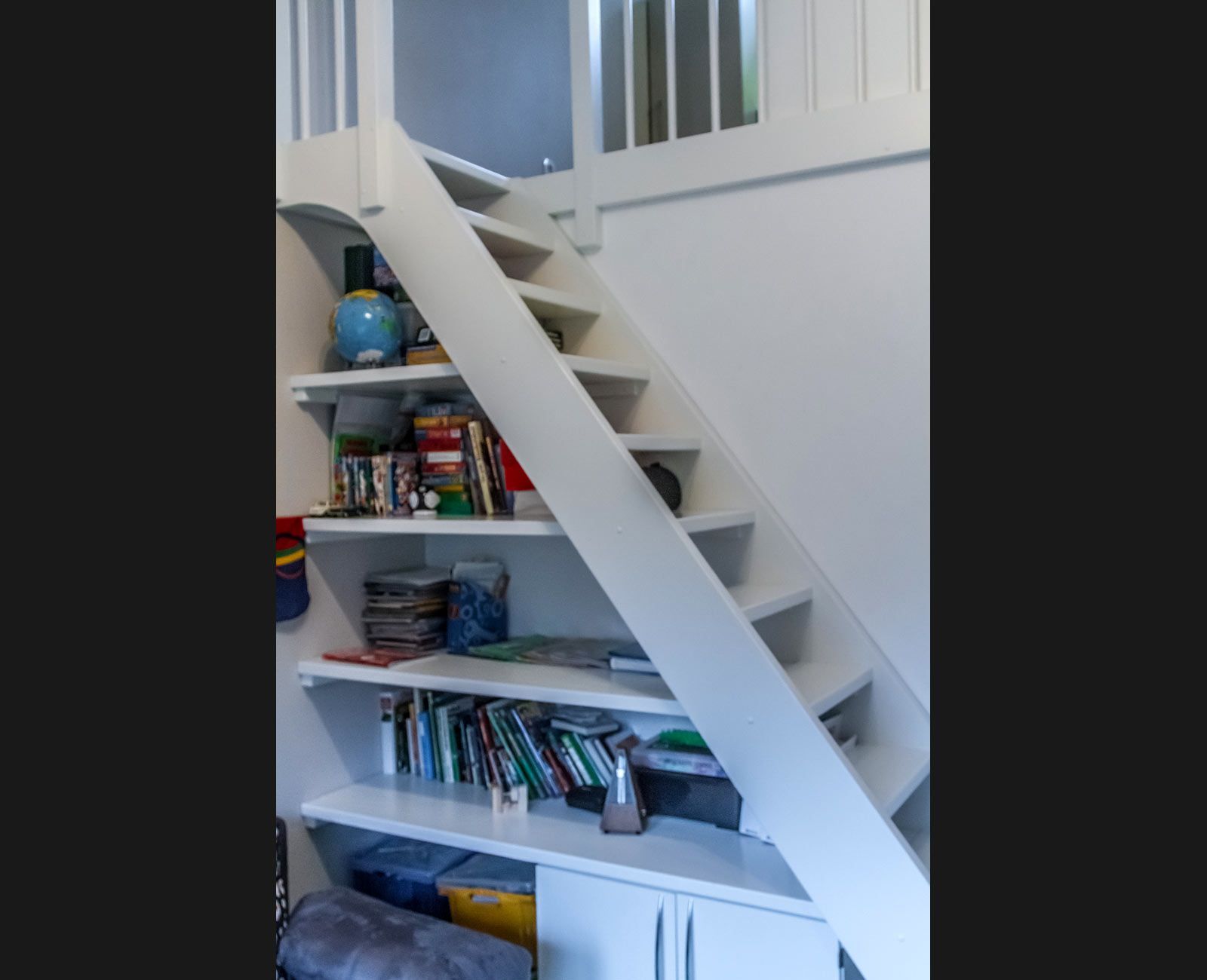 Eine weiße Treppe mit einem Bücherregal darunter