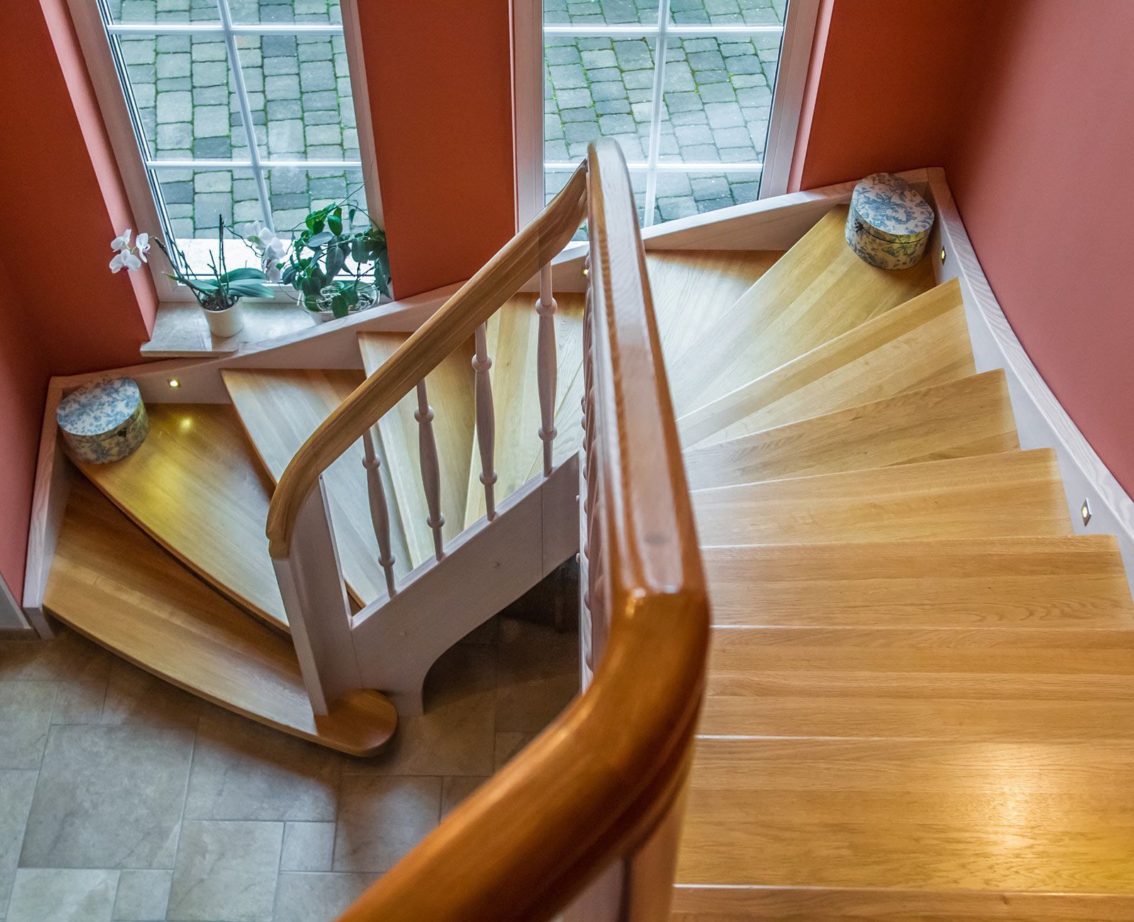 Eine hölzerne Wendeltreppe mit einem Fenster im Hintergrund