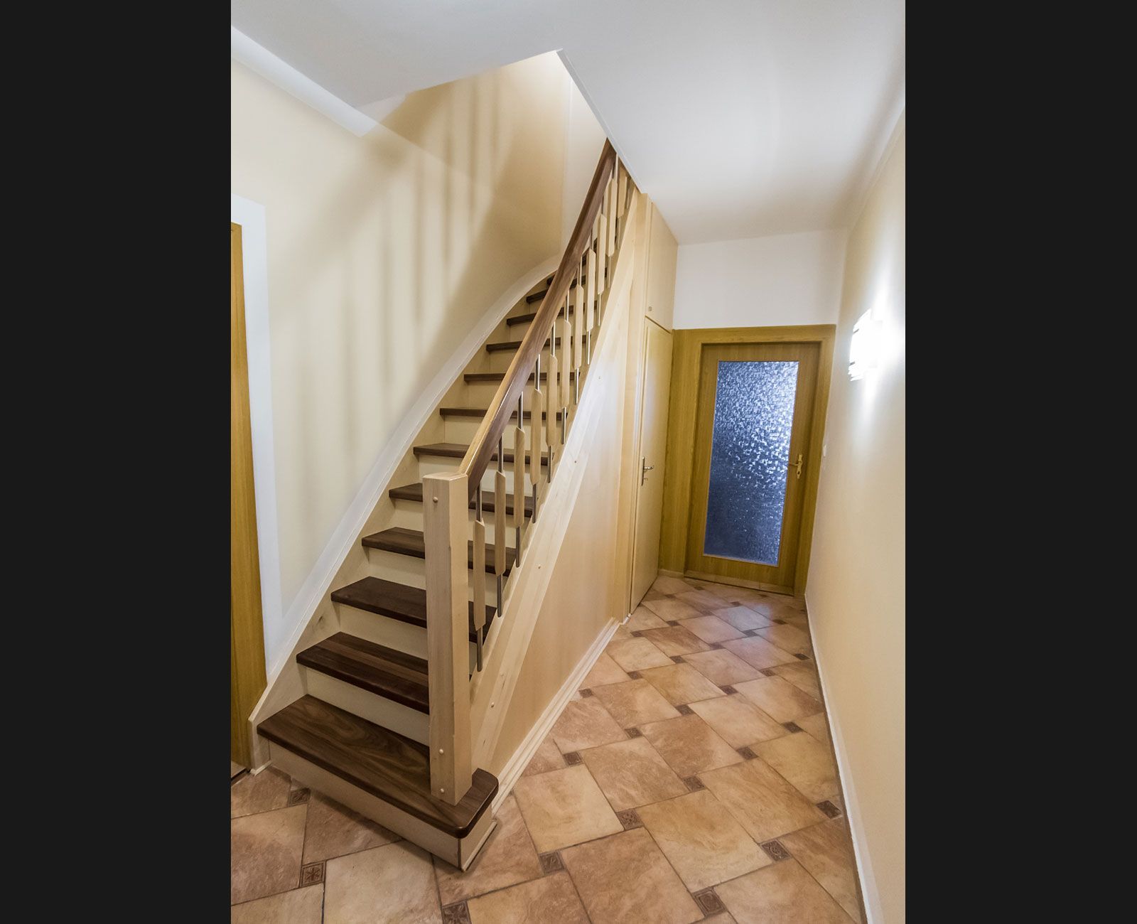 Eine Holztreppe in einem Flur mit einer Glastür.