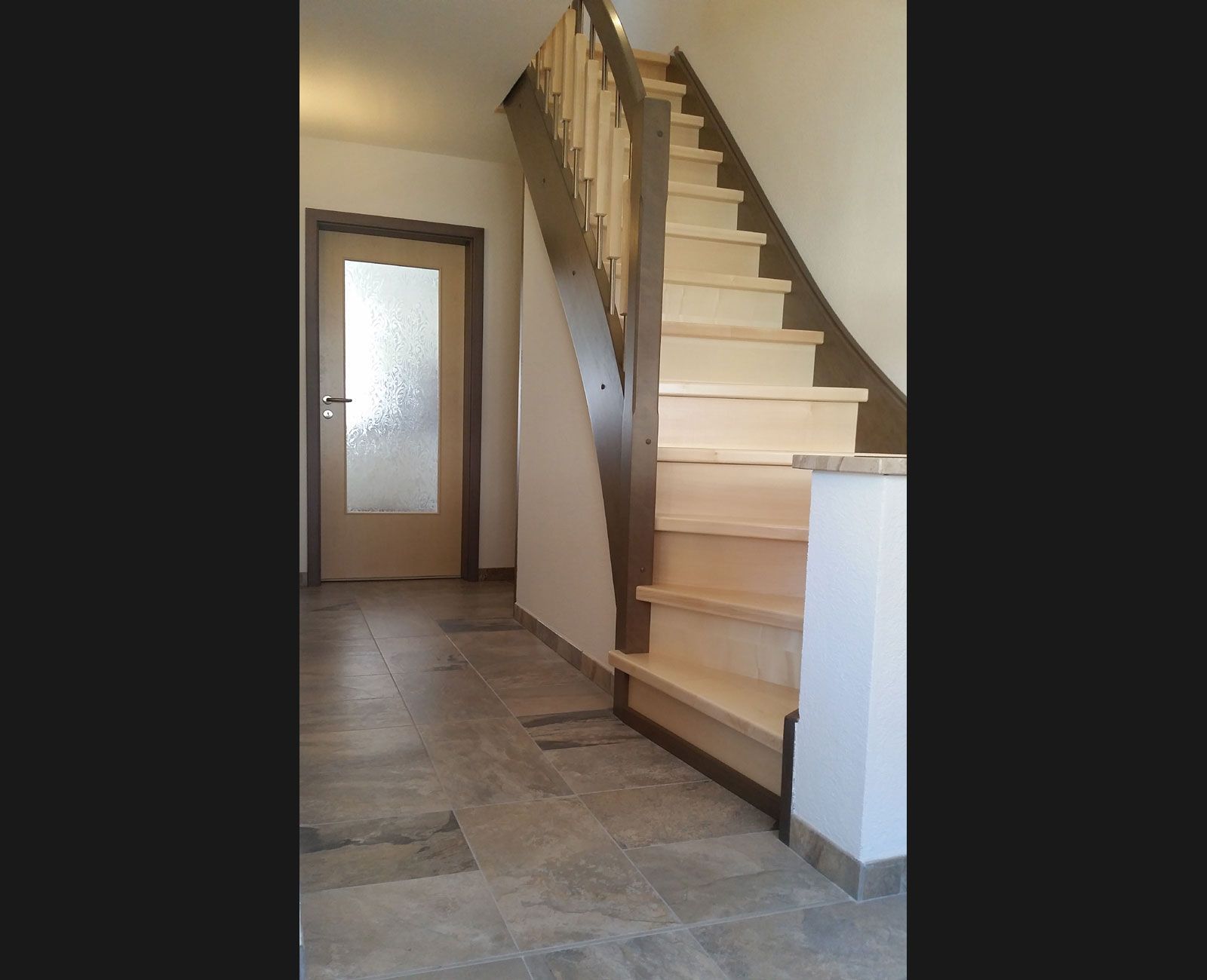 Eine Holztreppe in einem Flur mit einer Glastür