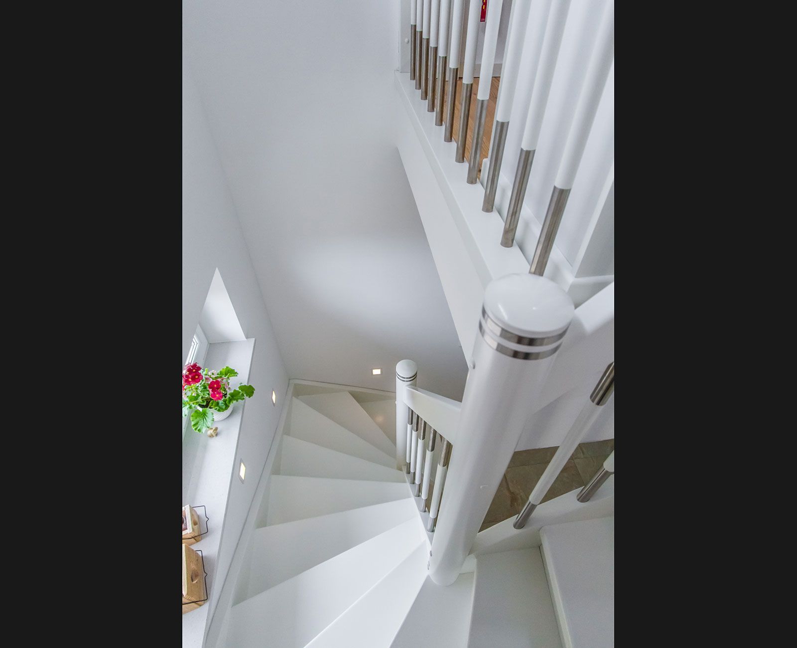 Eine weiße Wendeltreppe führt in den zweiten Stock eines Hauses.