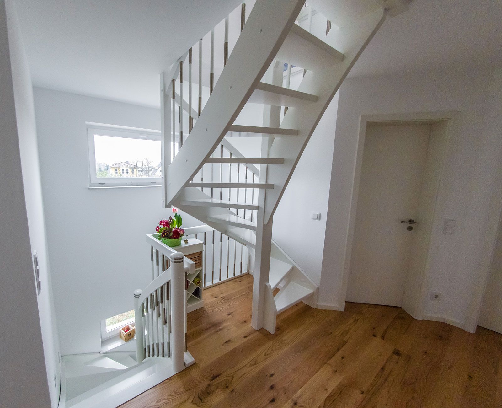 Eine weiße Holztreppe mit Holzboden in einem Flur.