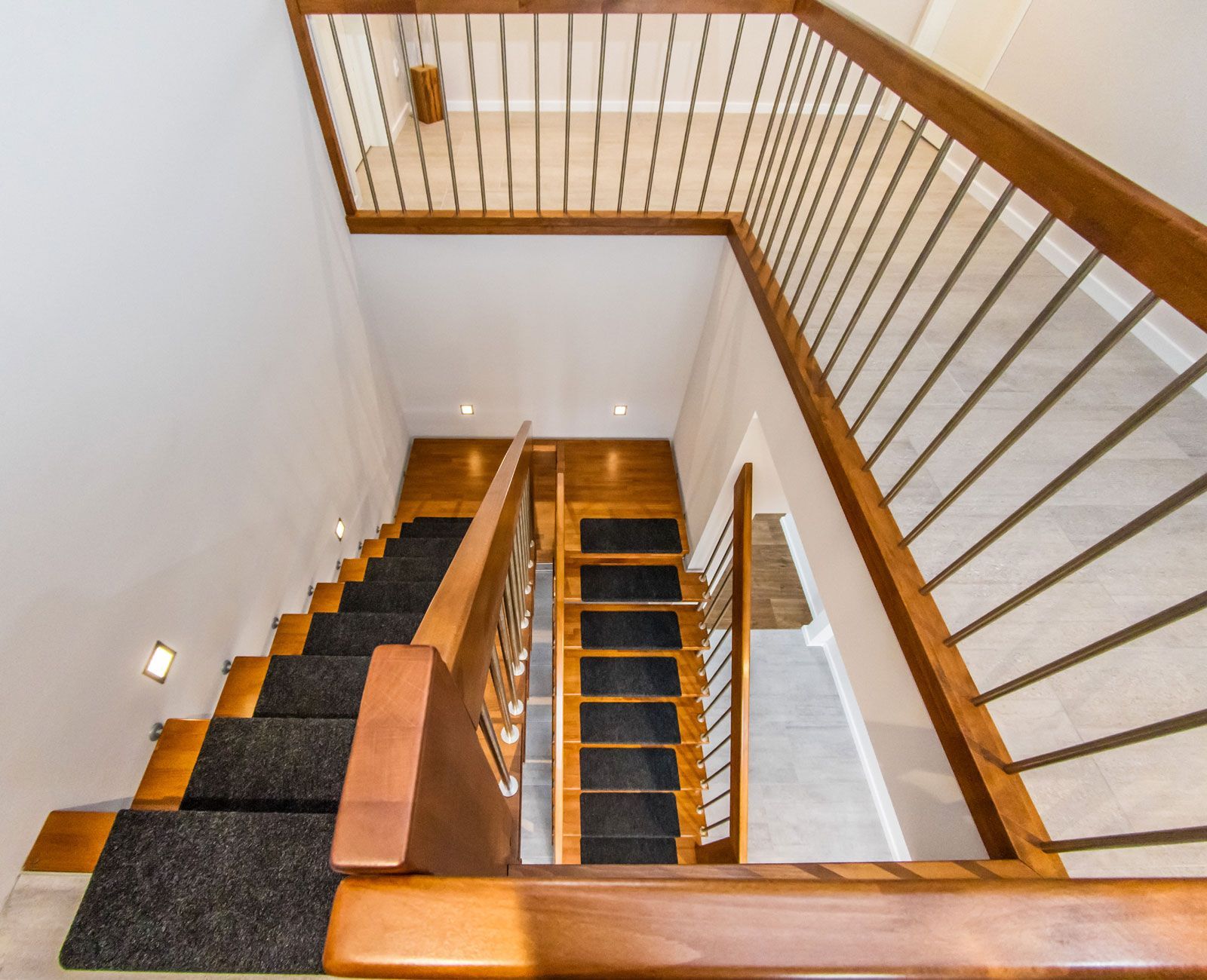 Eine Holztreppe mit Metallgeländer und schwarzem Teppich