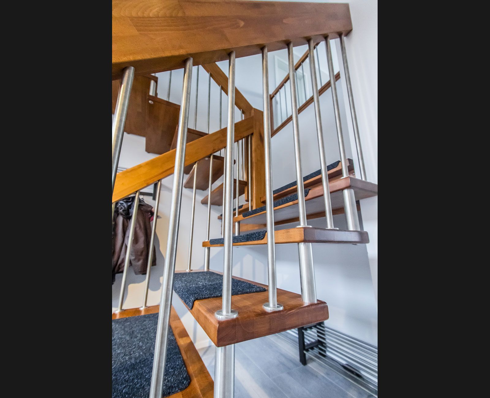 Eine hölzerne Wendeltreppe mit Geländer und Stufen aus Edelstahl.