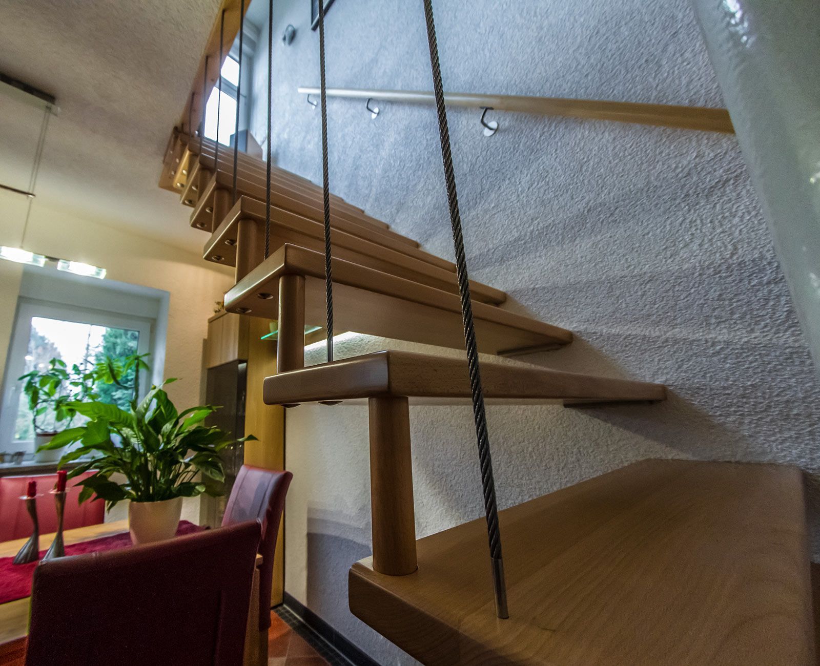 Eine Holztreppe mit Glasgeländer in einem Wohnzimmer