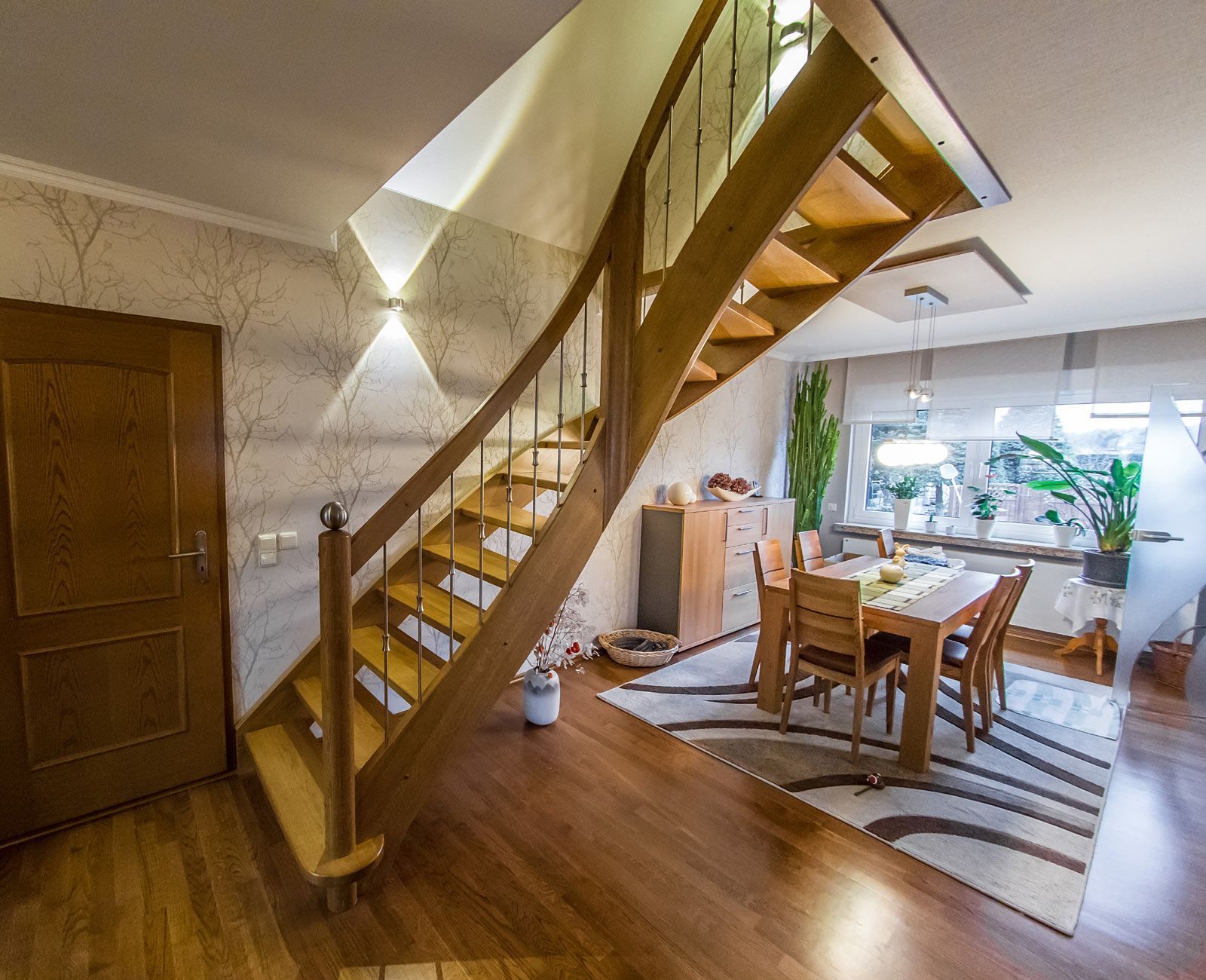 Eine Holztreppe in einem Wohnzimmer mit einem Tisch und Stühlen