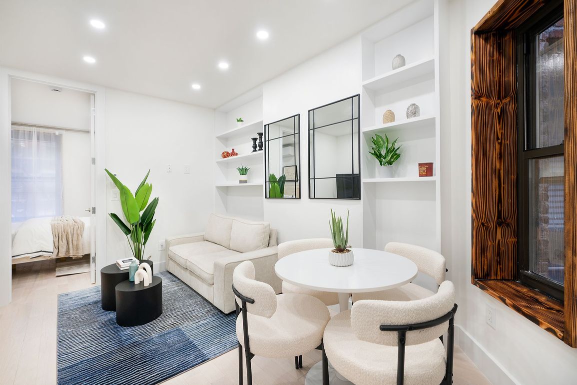Bright living space with a white sofa, round table, and built-in shelving.