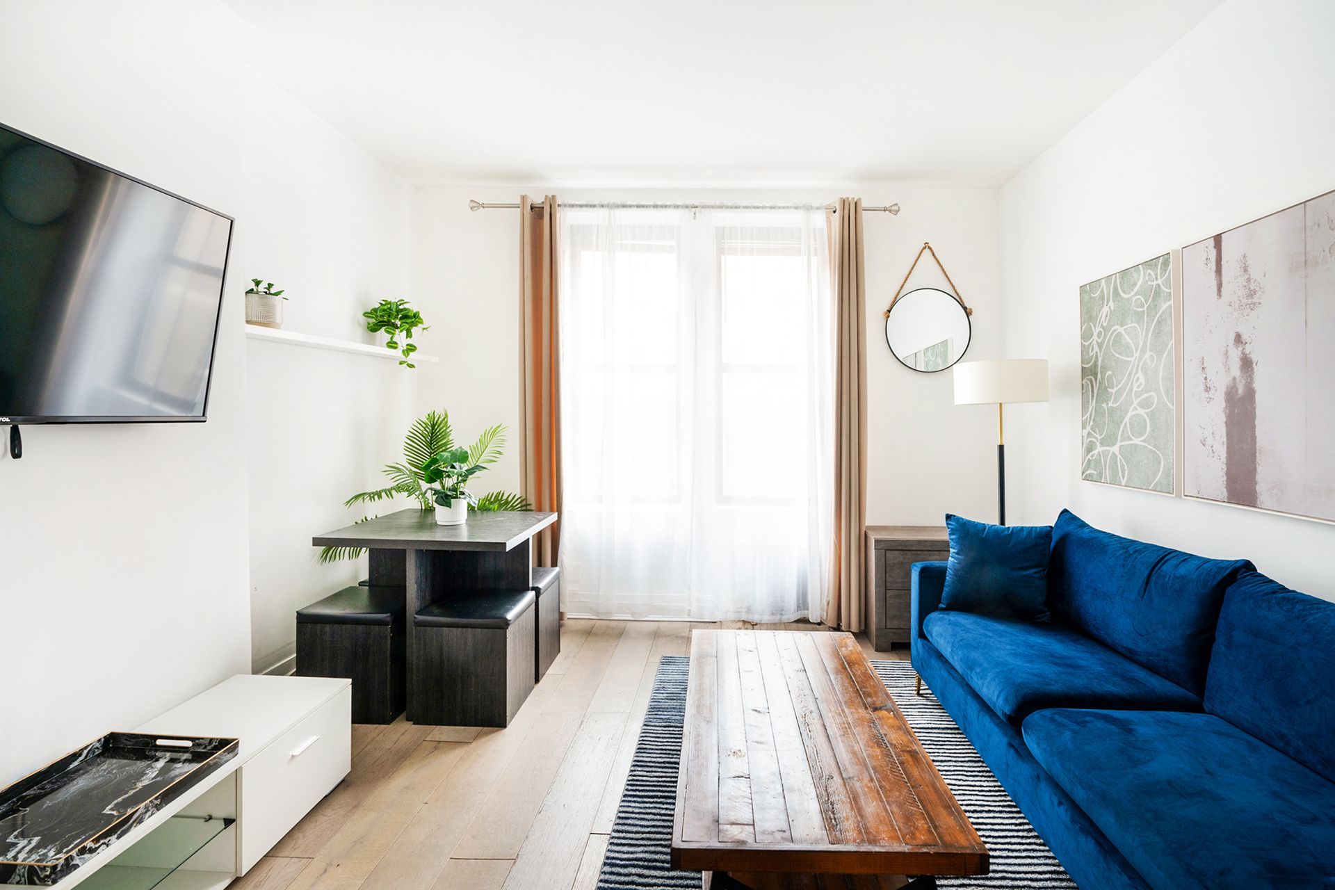 Stylish two-bedroom apartment with a living room that includes a blue sofa, wooden coffee table, decorative art pieces on the wall, and a blue area rug. Located in Midtown West.