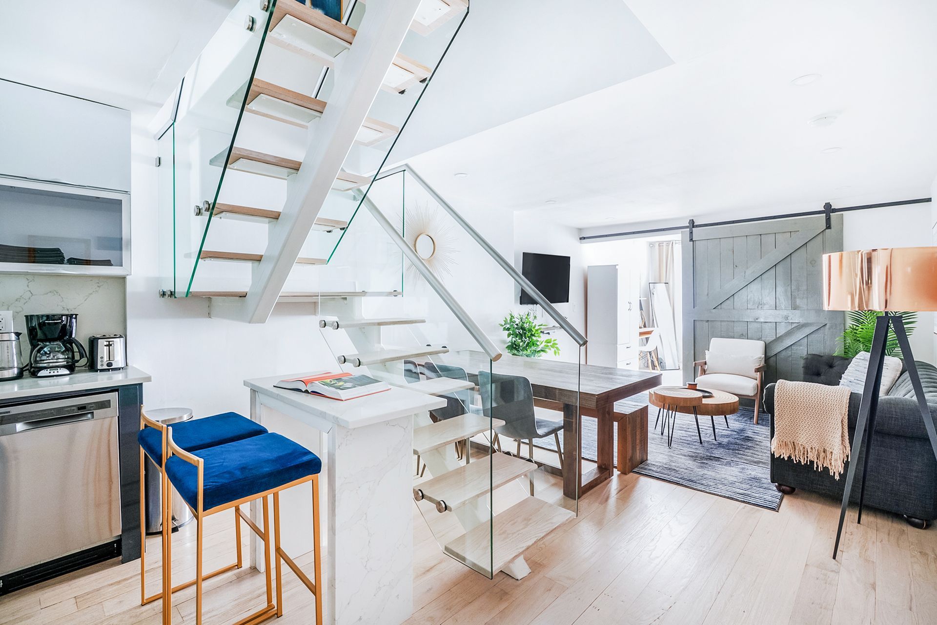 Three-bedroom apartment with kitchen, countertops, glass staircase, sofa, and coffee table. The apartment has a washer/dryer.