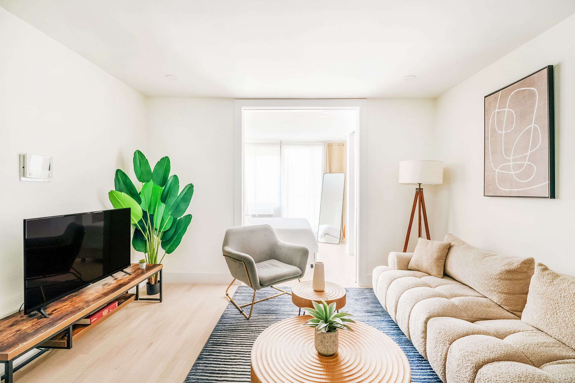 Bright three-bedroom apartment with a modern kitchen, white countertops, glass staircase, red armchair, and wooden coffee table. The apartment has a washer and dryer and an in-unit elevator.