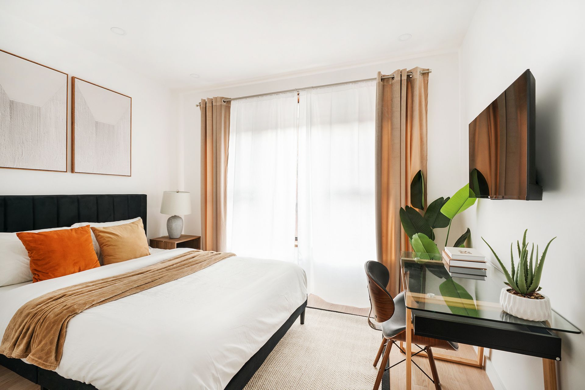 1-bedroom apartment with sofa, coffee table, white bed, wall art, frosted glass doors. The apartment has a dishwasher/dryer.