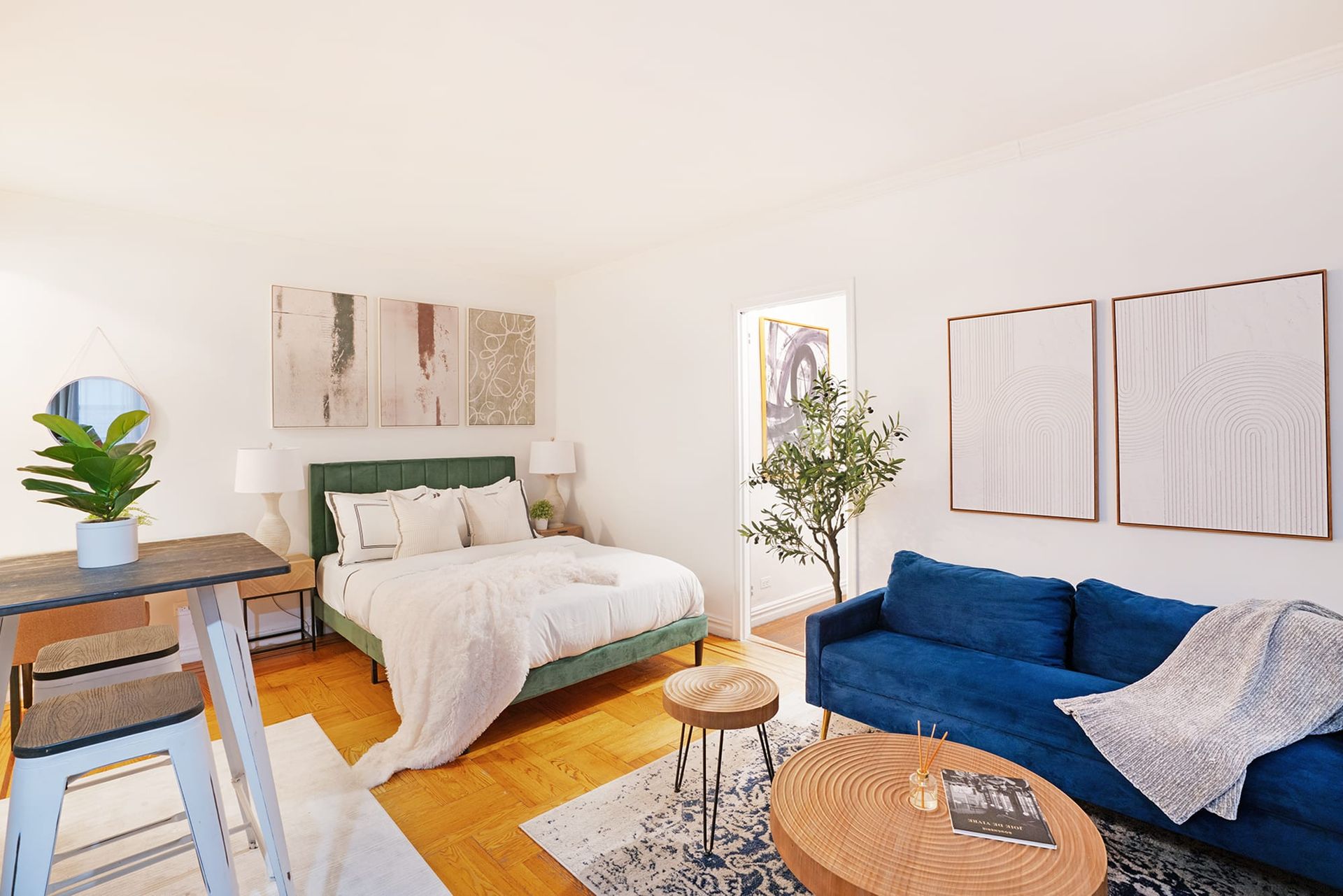 Studio apartment featuring a green bed, wooden floor, wooden coffee table, and modern decor. Located in Gramercy/Murray Hill.