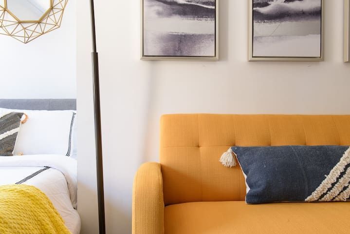 Stylish studio apartment featuring a yellow armchair, light decor, and a washer and dryer. Located in Gramercy/Murray Hill.