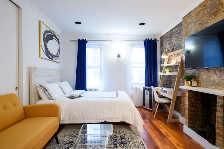 Charming studio apartment with  bed, exposed brick wall, blue curtains, and a washer/dryer. Located in Gramercy/Murray Hill.