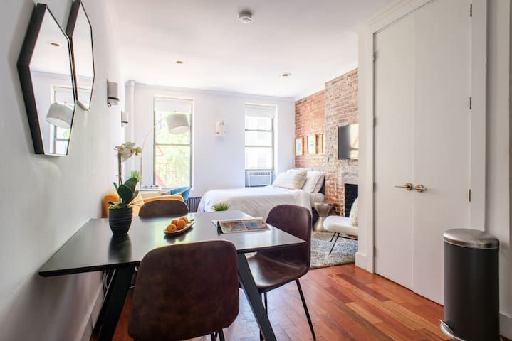 Contemporary studio apartment with bed, brick wall, dining area, and a washer and dryer. Located in Gramercy/Murray Hill.