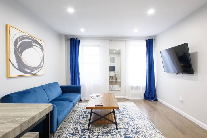 1 bedroom apartment with a blue sofa, a wooden coffee table, and a blue patterned rug. Features bright lighting and modern decor. Located in Gramercy/Murray Hill.