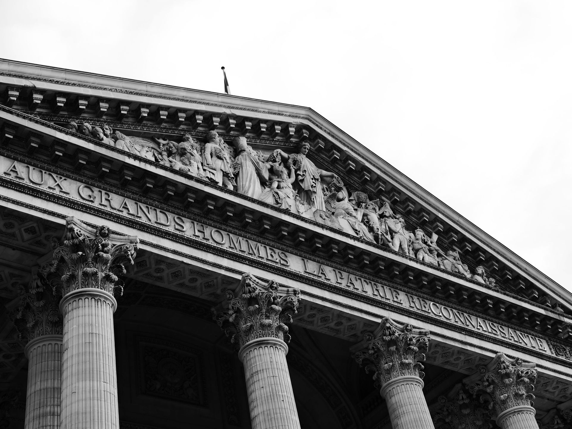Façade classique d'un palais de justice avec colonnes et fronton sculpté se détachant sur un ciel lumineux
