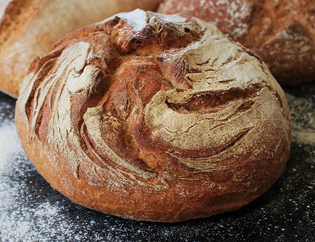 Pyöreä maalaismainen rapea leipä, jonka tummalla pinnalla on jauhoja.