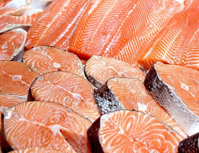 Tuoreita lohifileitä pinottuna yhteen, kirkkaan oranssi liha ja hopeanhohtoinen nahka